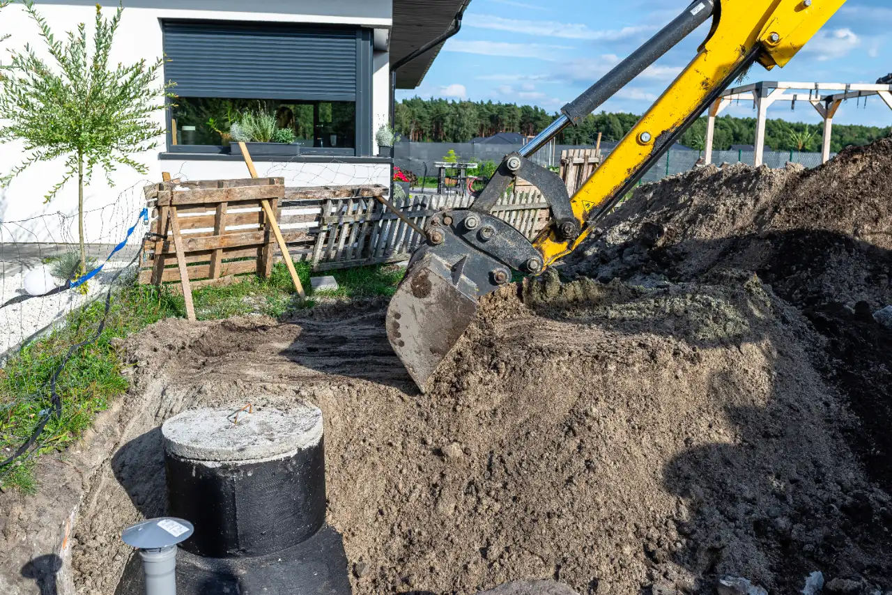 Excavator burying concrete septic tank